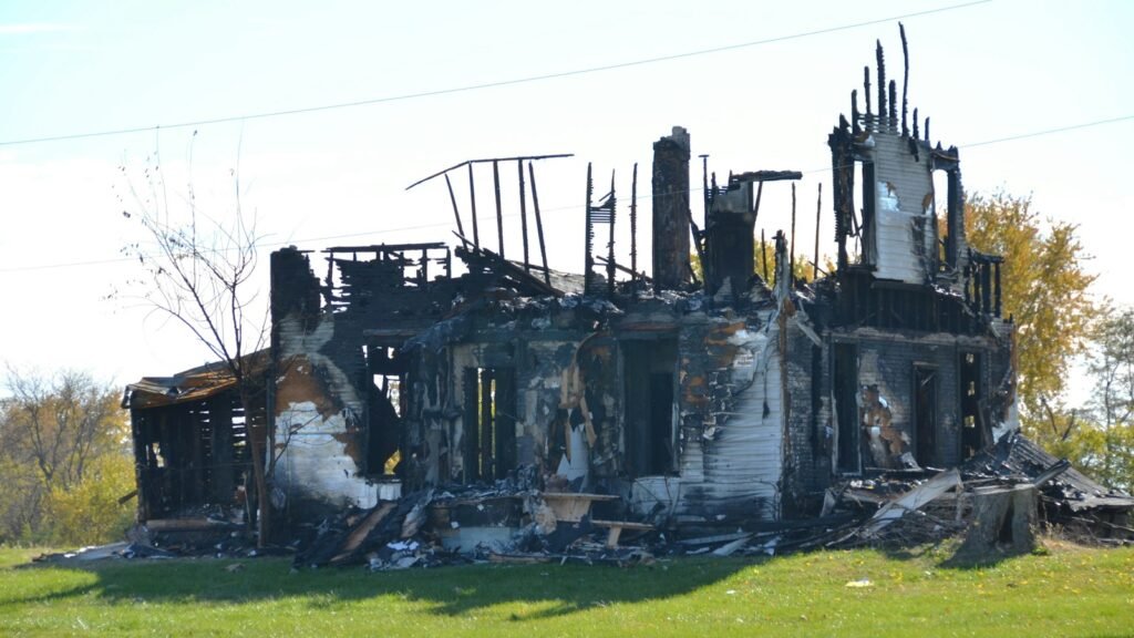 Charred remains of a white house destroyed by fire, showing the kind of total loss behind many claims