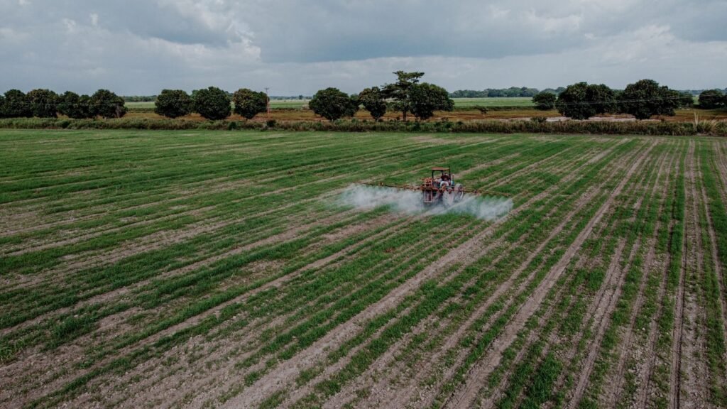 Aerial view of a tractor spraying a green field, the work at the center of a chlorpyrifos Parkinson's lawsuit