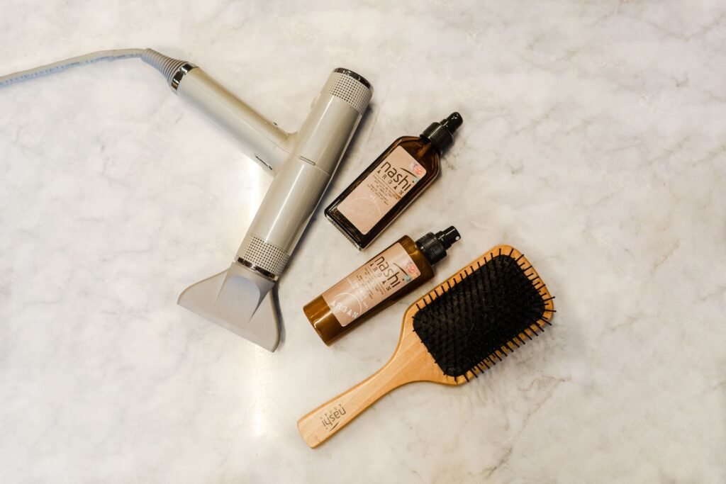 Hairbrush, hair dryer and styling products on a marble table, illustrating products in the hair relaxer MDL