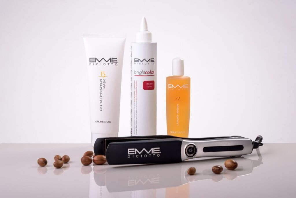 Hair care products and a flat iron arranged on a reflective surface