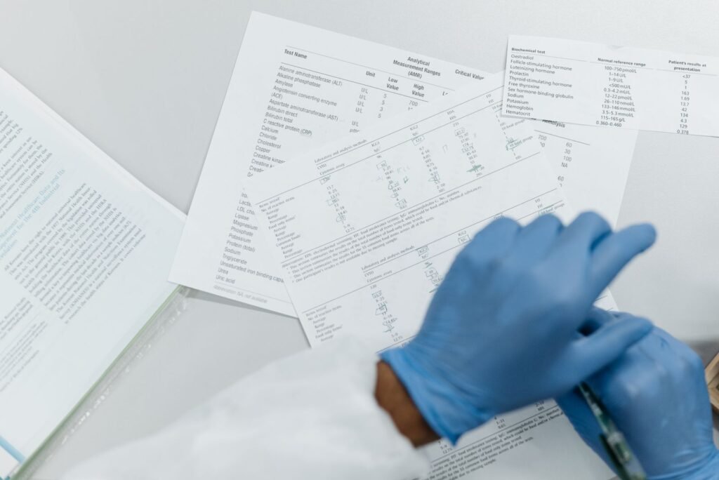 Gloved hands reviewing printed lab test results on a white surface