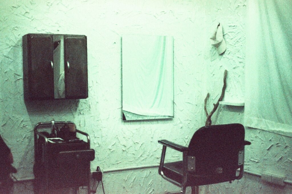 Empty salon chair and mirror against a green wall, where smoothing treatments are often done