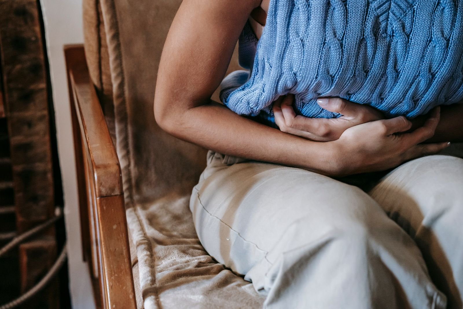 Hernia mesh complications: person holding the lower abdomen in pain while seated