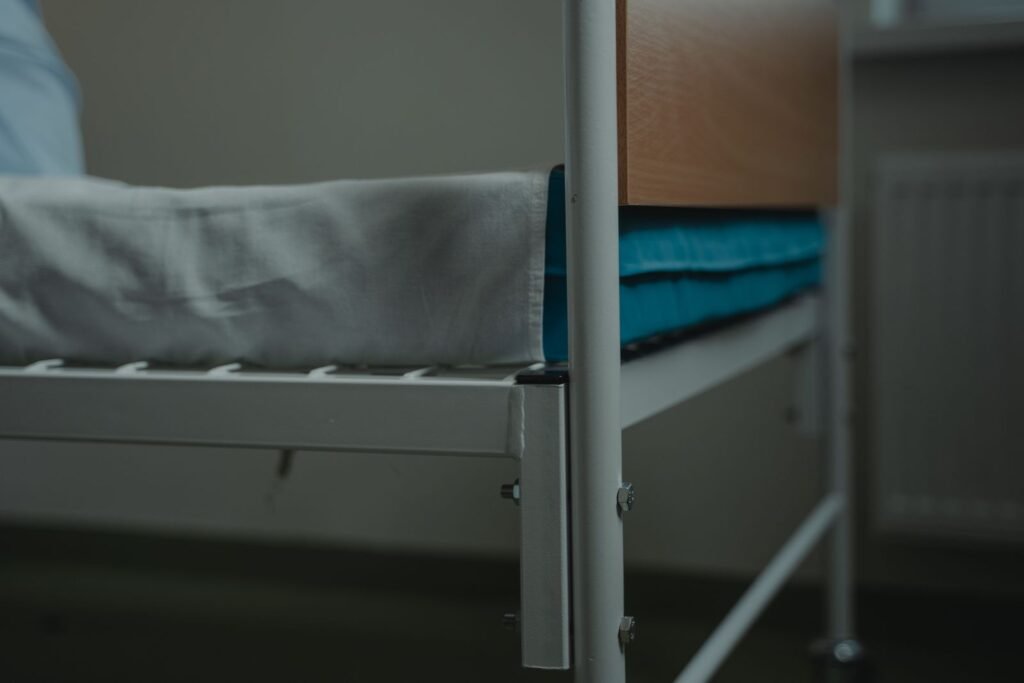 Close-up of a hospital bed with white linens and a metal frame