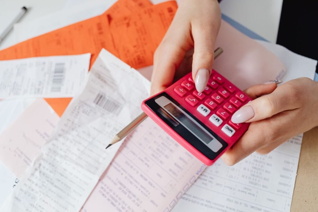 Hands using a calculator beside receipts and medical bills on a desk