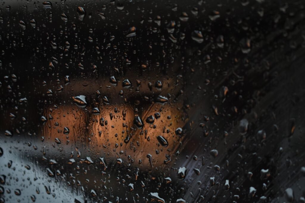 Raindrops on a car window at night with blurred street lights, reflecting what rideshare assault survivors may feel