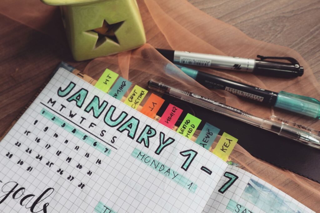 Open planner with colored tabs and pens on a wooden desk for tracking appointments and records