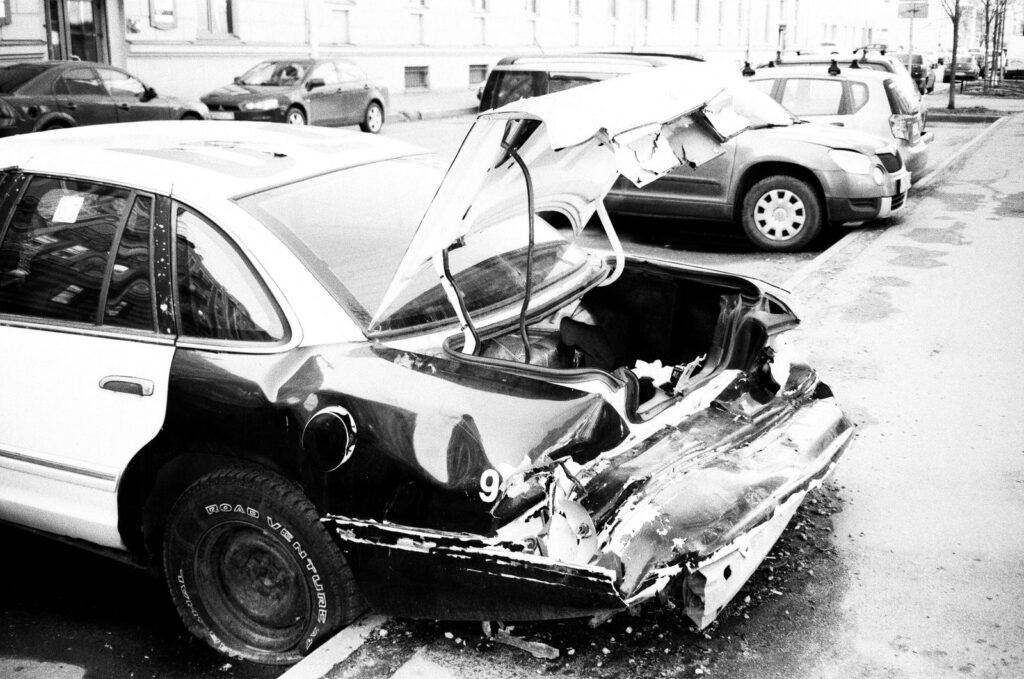 Black and white photo of a wrecked car on a city street after a crash covered by Uber or Lyft accident insurance