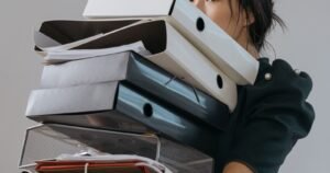 Person carrying a stack of file folders, representing records that may support an LDS abuse lawsuit