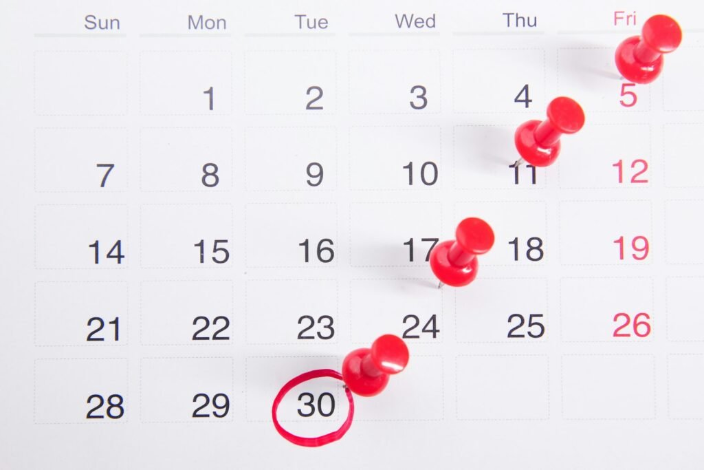Wall calendar with red push pins marking important filing dates