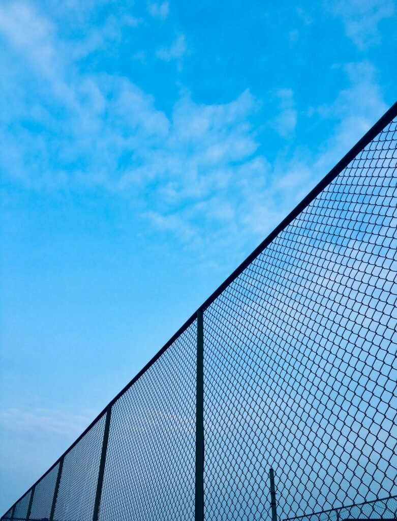 Chain-link fence under a blue sky, a reminder of the locked settings at the center of Maryland juvenile facility abuse claims