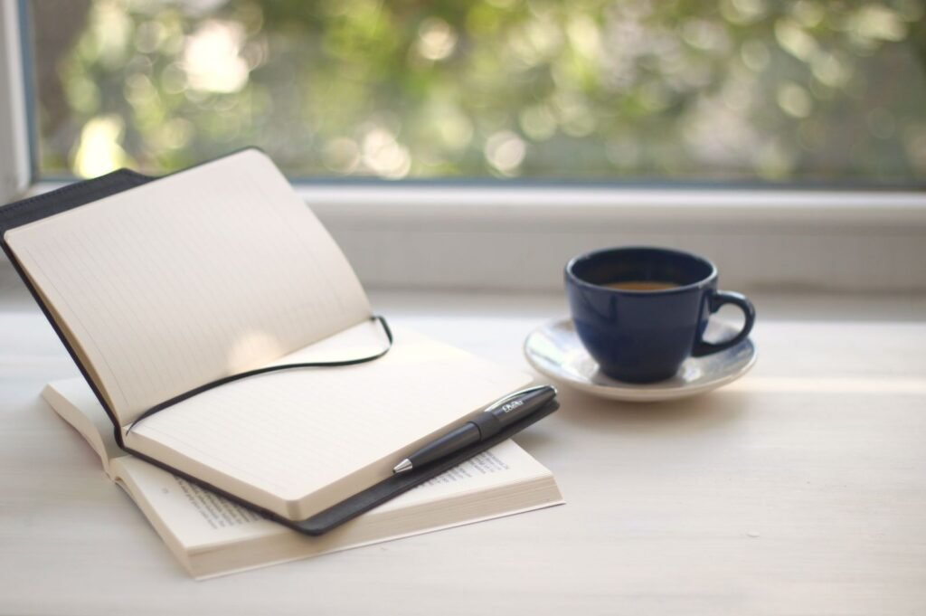 Open notebook and coffee cup on a sunlit windowsill