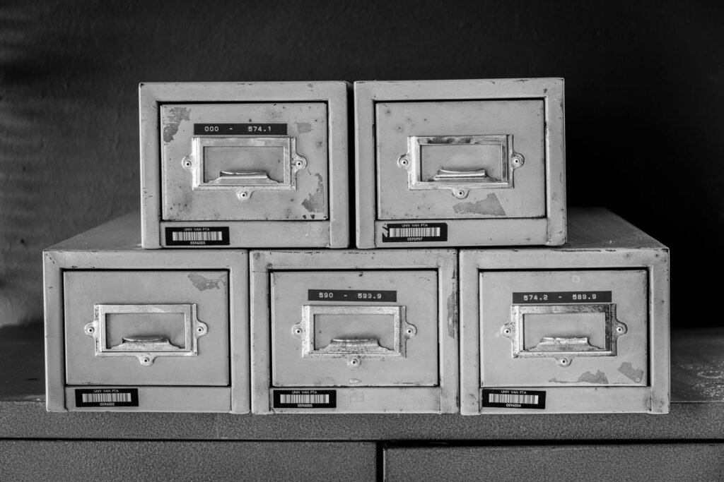 Row of five vintage metal file cabinets in black and white, representing old work records
