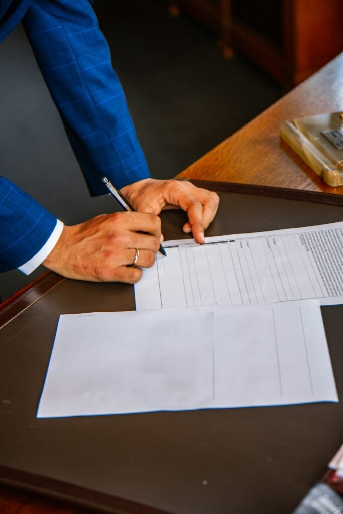 Hand filling out a paper form with a pen on a desk