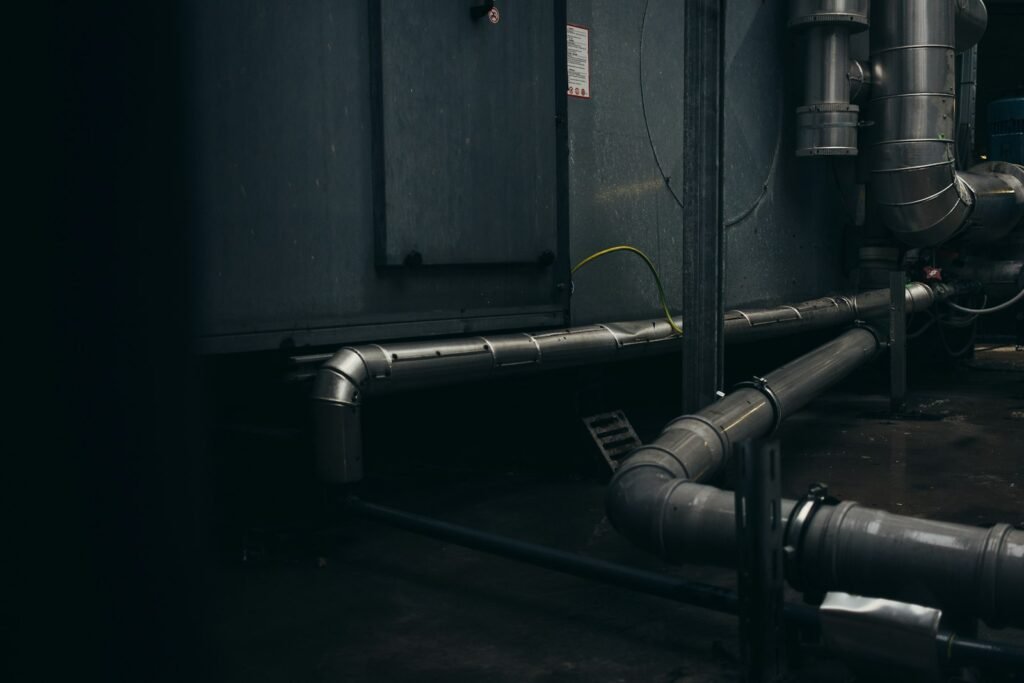 Gray industrial pipes on a concrete wall, the type of work site often reviewed in mesothelioma lawsuits