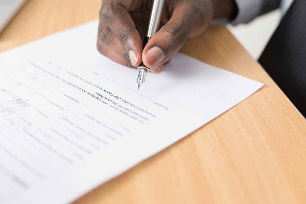 Hand signing paperwork, a reminder to read forms carefully during the motor vehicle accident lawsuit steps