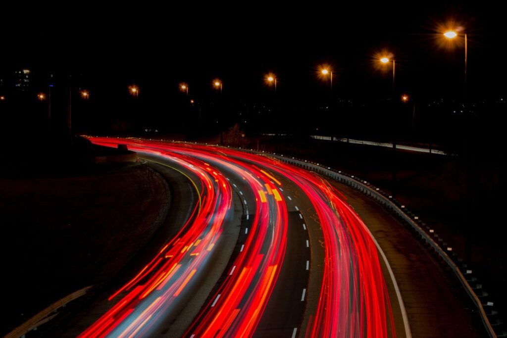 Long exposure of a highway at night with light trails from passing cars under streetlamps