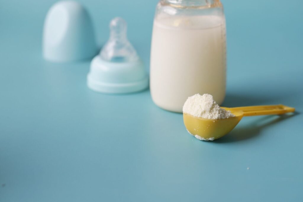 Scoop of powdered baby formula beside a bottle, raising questions about NEC and preemie formula