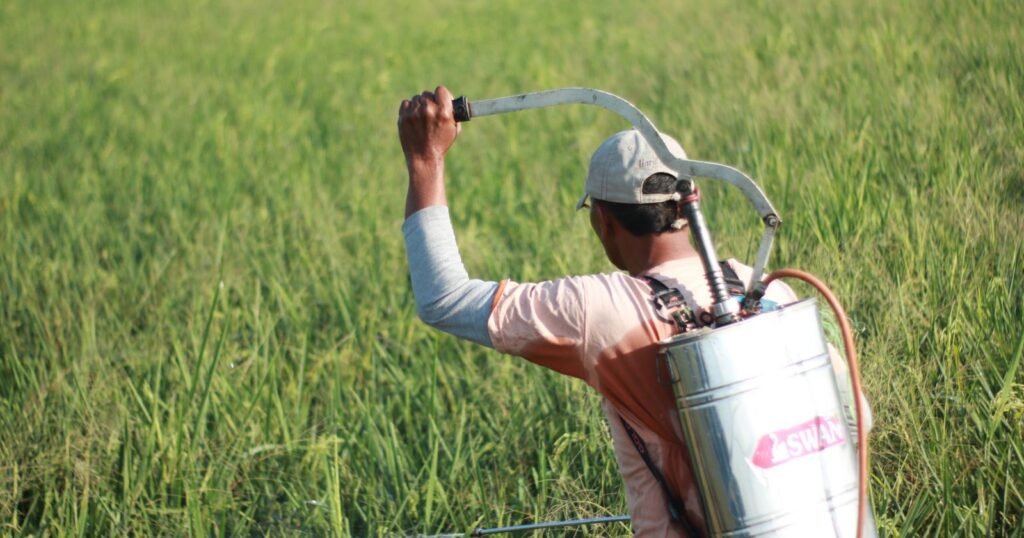 Farmer spraying a field with a backpack sprayer, illustrating proof of exposure in a paraquat exposure lawsuit