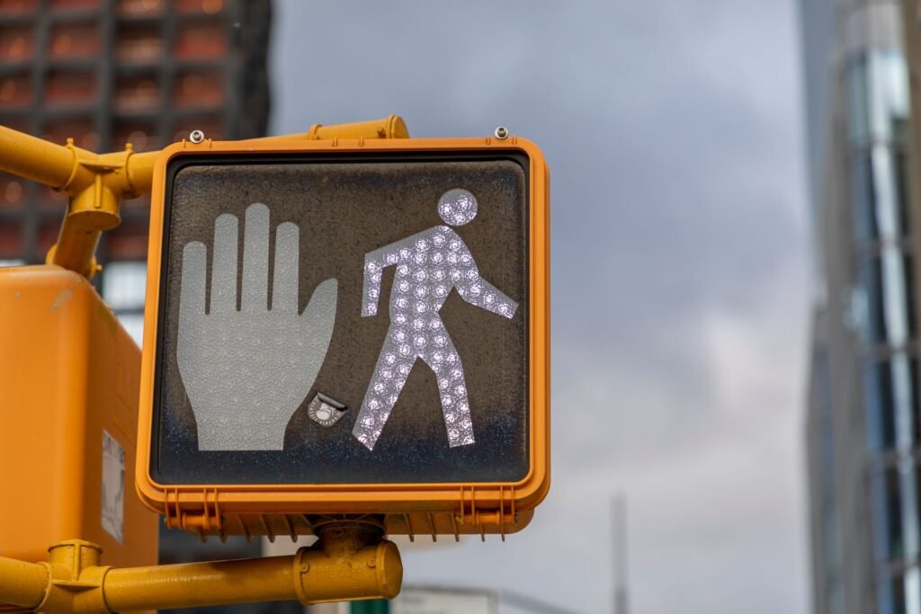Illuminated pedestrian crosswalk signal on a city street with buildings in the background