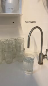 PFAS lawsuits: clean drinking glasses beside a kitchen faucet, representing PFAS in tap water