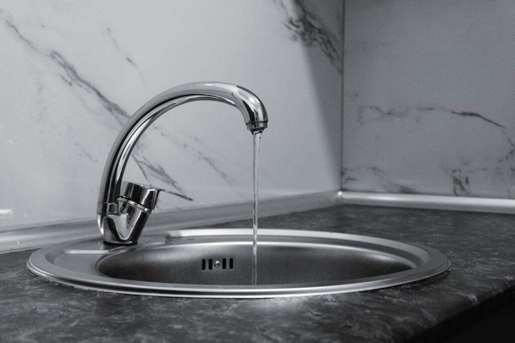 Chrome kitchen faucet with running water over a sink