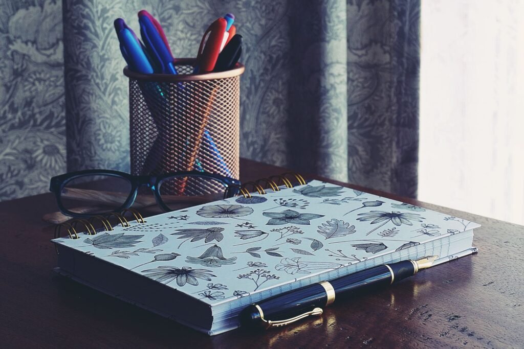 Notebook, glasses and pens on a wooden desk, ready for writing a witness statement
