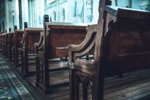 Rhode island revival window: rows of empty wooden church pews in a sunlit church