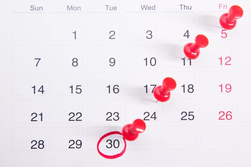 Calendar with red push pins marking important dates and deadlines