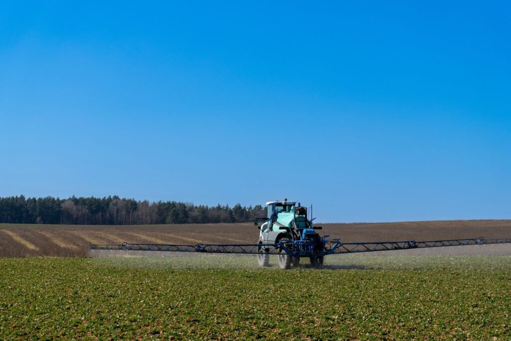 Tractor with spraying equipment treating crops on a sunny day