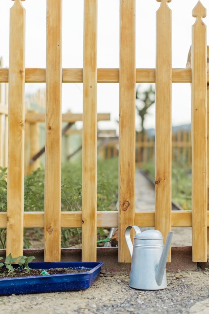 Backyard garden with a wooden fence and metal watering can, typical of a Roundup lawsuit for homeowners