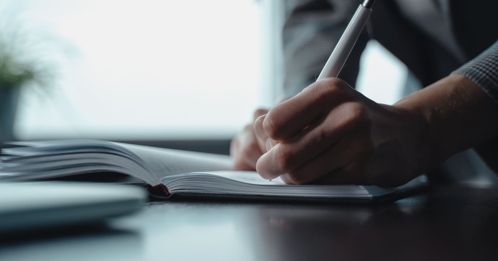 Person writing notes in a notebook at a quiet desk, representing the school abuse lawsuit process