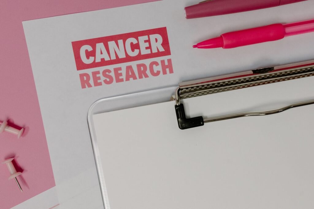 Cancer research paper on a clipboard with pink stationery on a desk