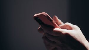Social media addiction lawsuit eligibility: hands scrolling on a smartphone in a dark room late at night