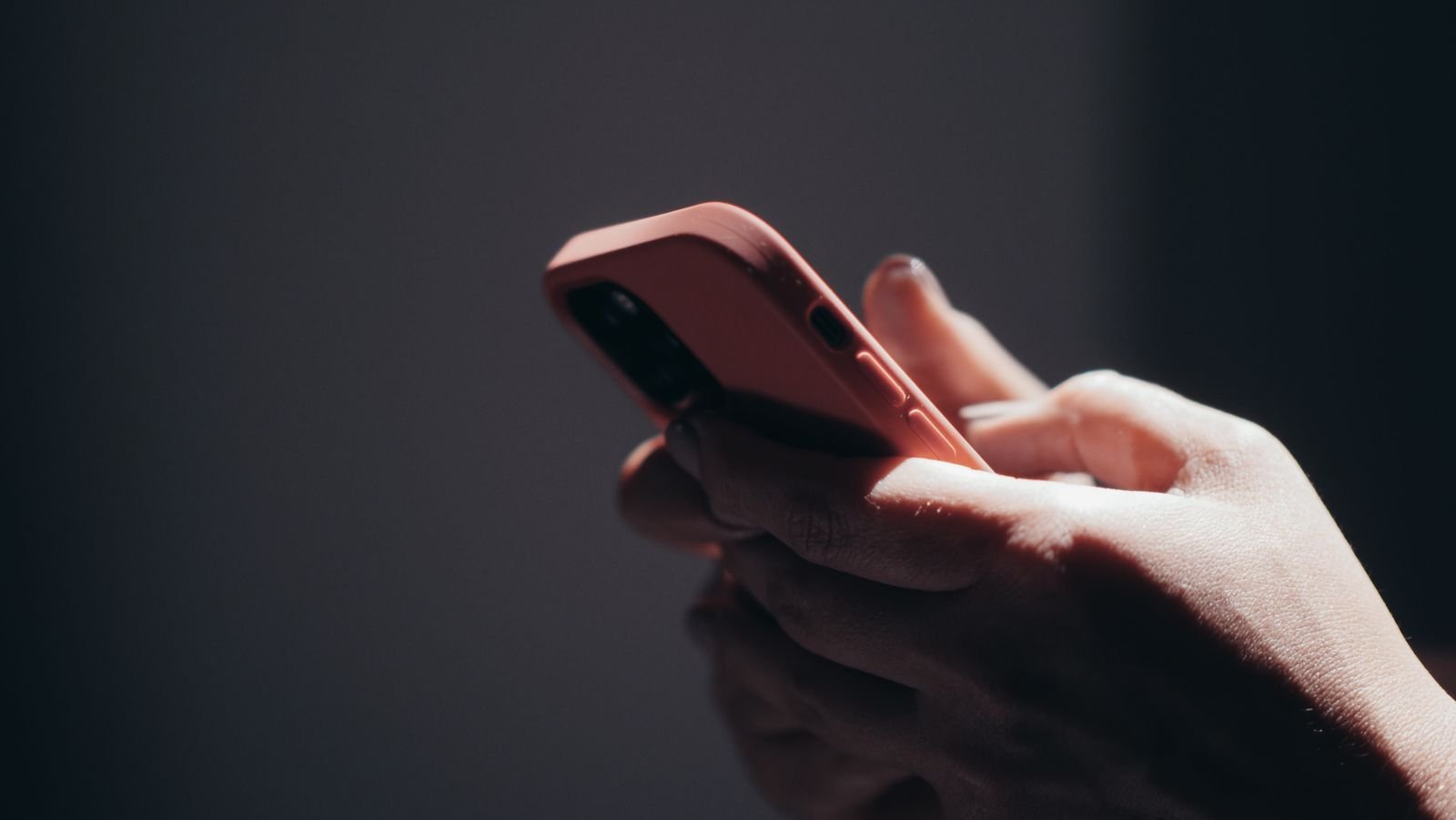 Social media addiction lawsuit eligibility: hands scrolling on a smartphone in a dark room late at night