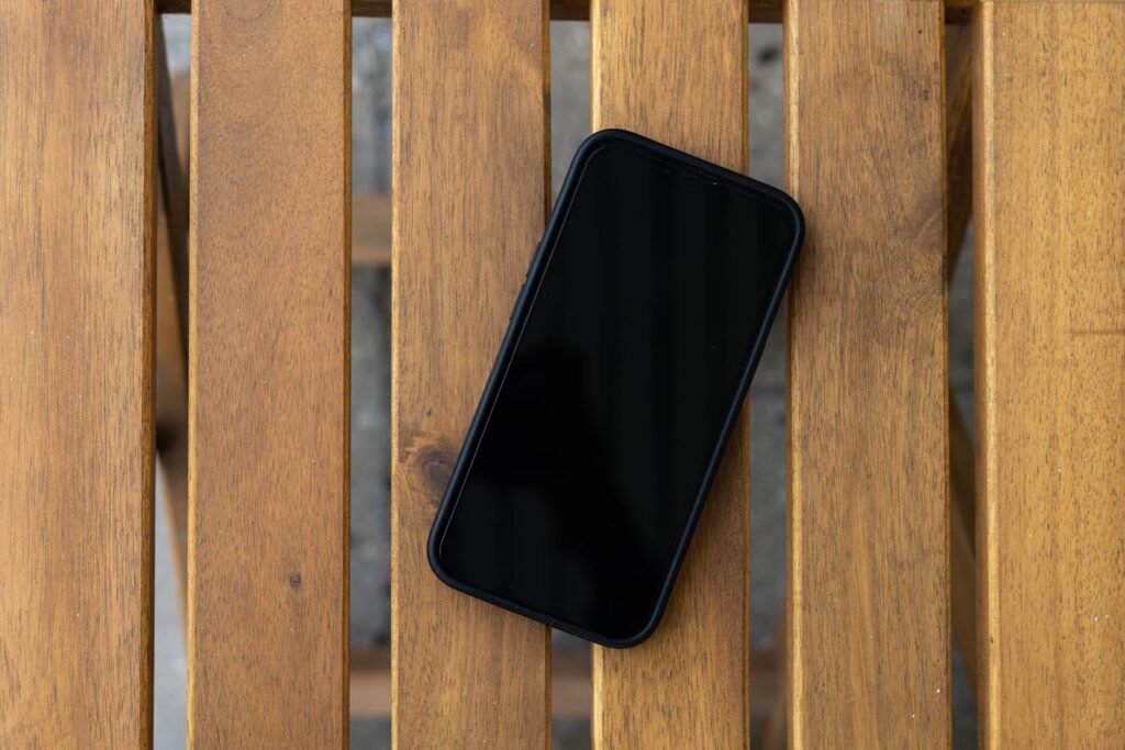 Smartphone with a dark screen on a wooden table, a symbol of questions about social media addiction lawsuit eligibility