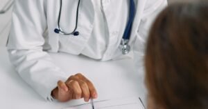 Doctor documenting SSDI medical evidence while meeting with a patient at a clinic desk
