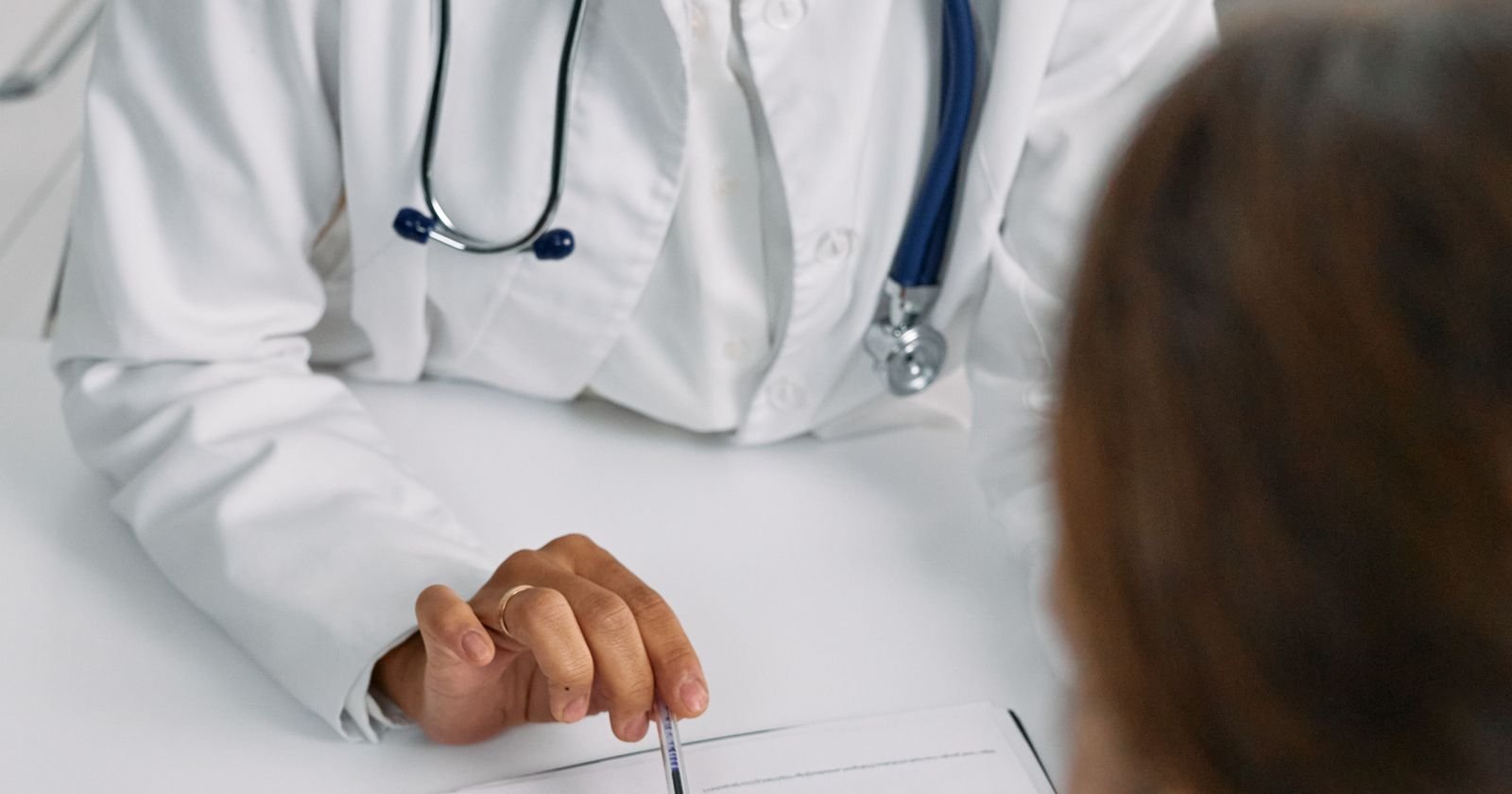 Doctor documenting SSDI medical evidence while meeting with a patient at a clinic desk