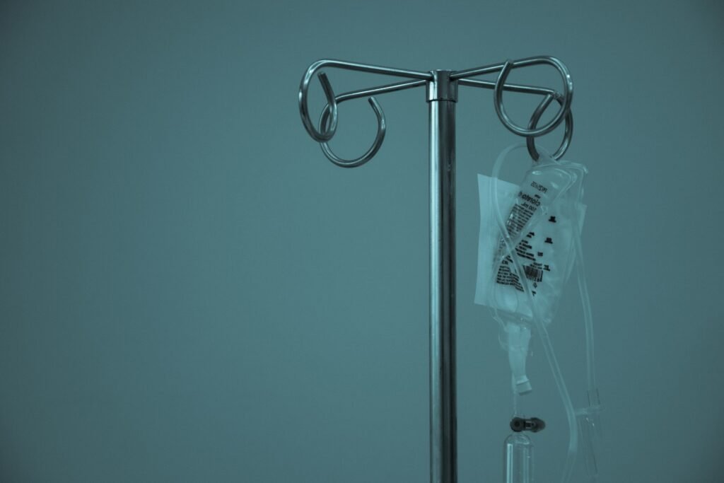 IV fluid bag hanging from a stainless steel stand in a treatment area