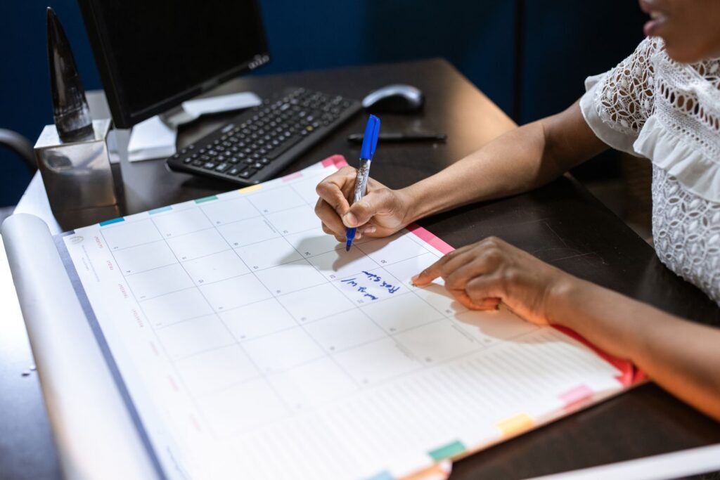 Hand writing appointments on a desk calendar to plan follow-up care in the week after a car accident