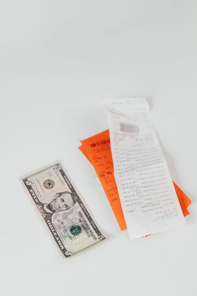 Dollar bill next to colorful receipts on a white surface, showing costs to track after a crash