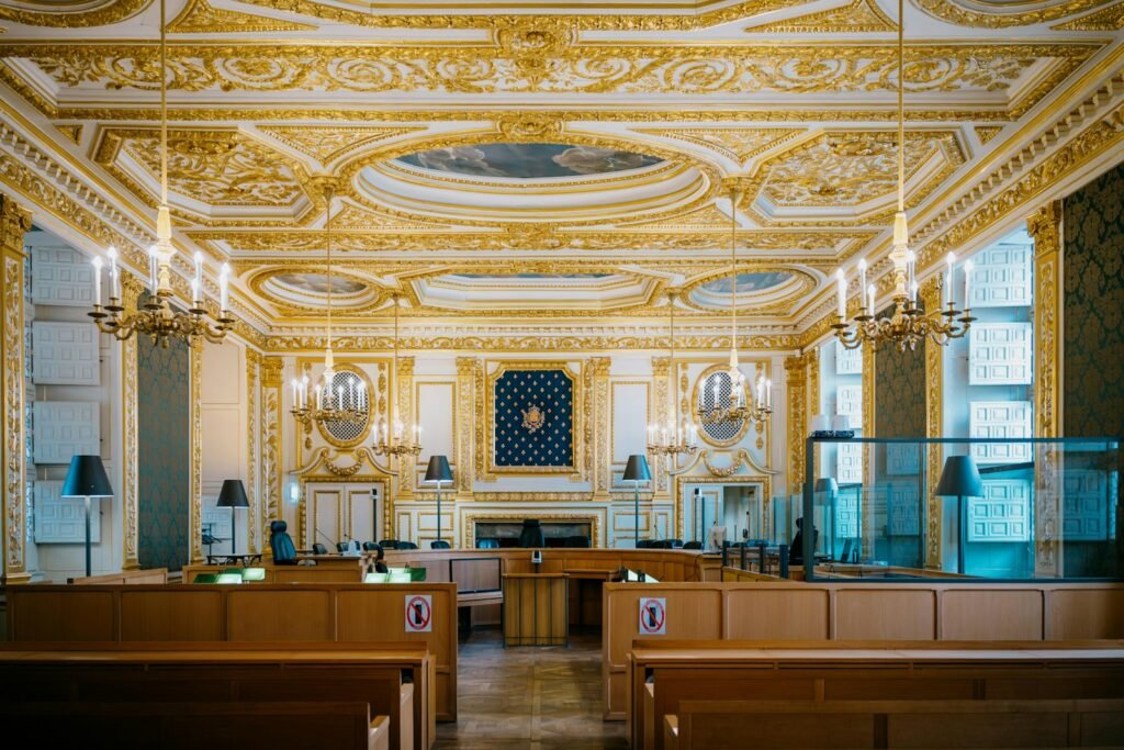 Empty ornate courtroom with wood paneling and chandeliers where a jury trial would be heard