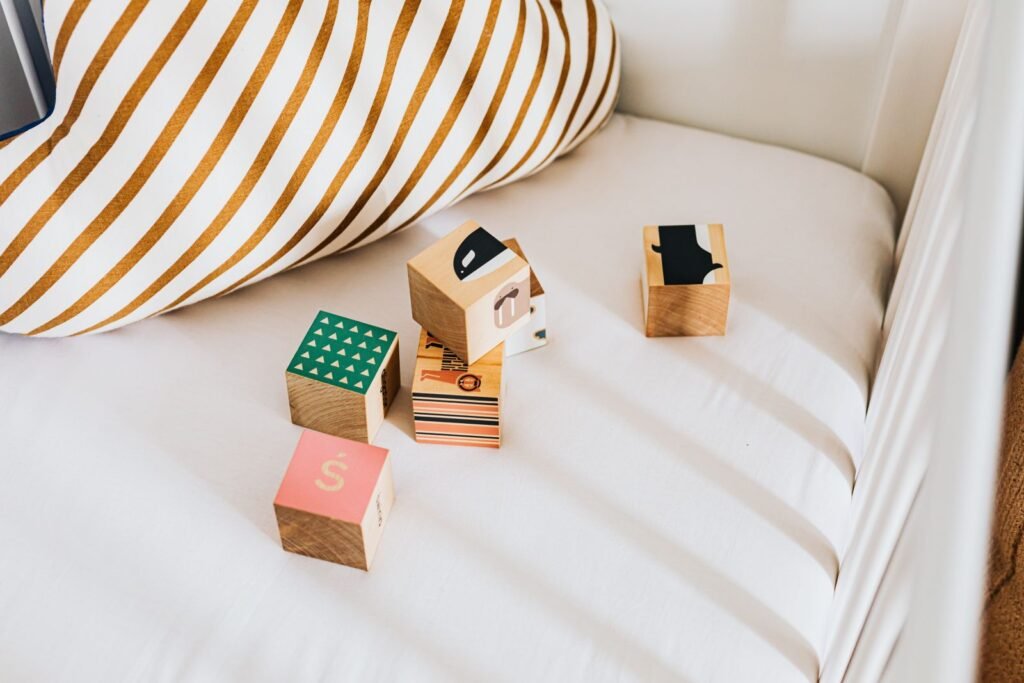Colorful wooden toy blocks resting on a white bed with a striped pillow