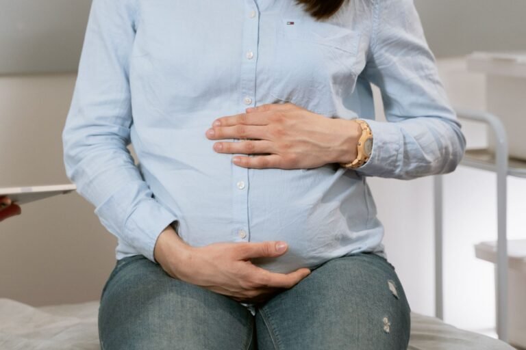 Pregnant woman sitting at home with her hands on her belly, illustrating the Tylenol pregnancy warning