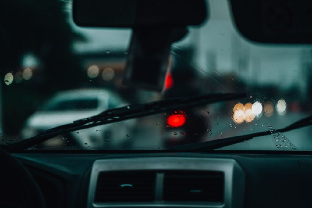 Raindrops on a car windshield with blurred city lights at night