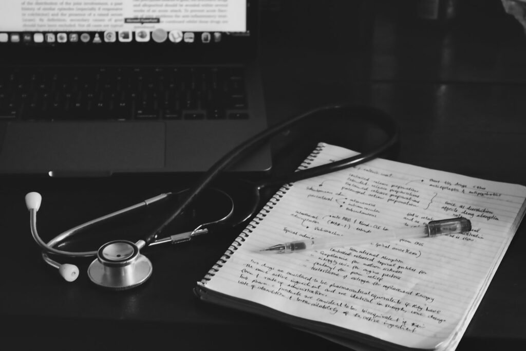 Stethoscope resting on a notebook next to a laptop, representing medical records and notes