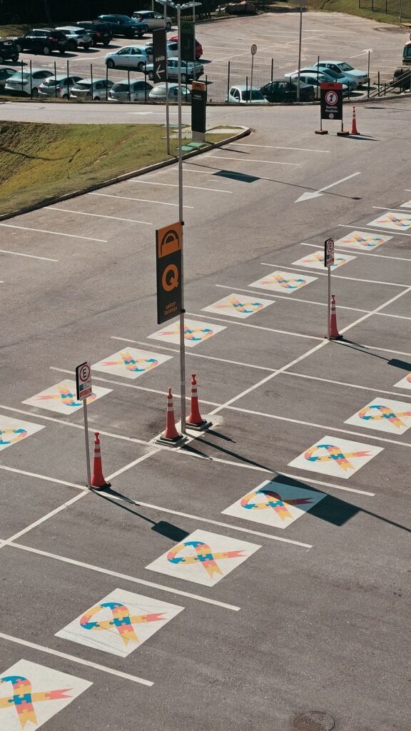 Aerial view of an empty parking lot with painted lane arrows, crosswalk and traffic cones