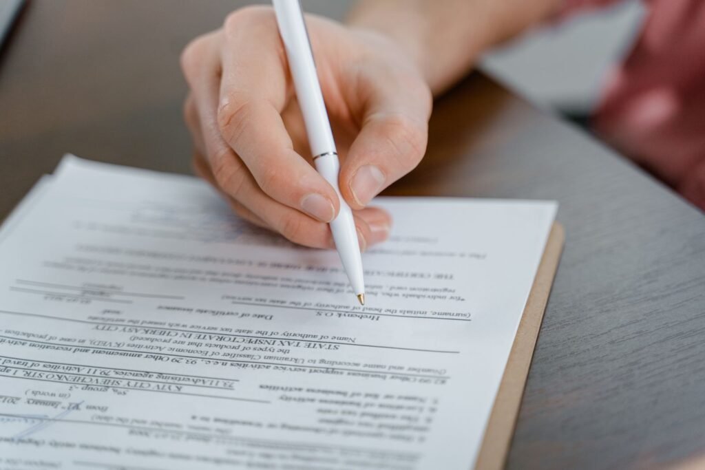 Close-up of a hand holding a pen while signing a document